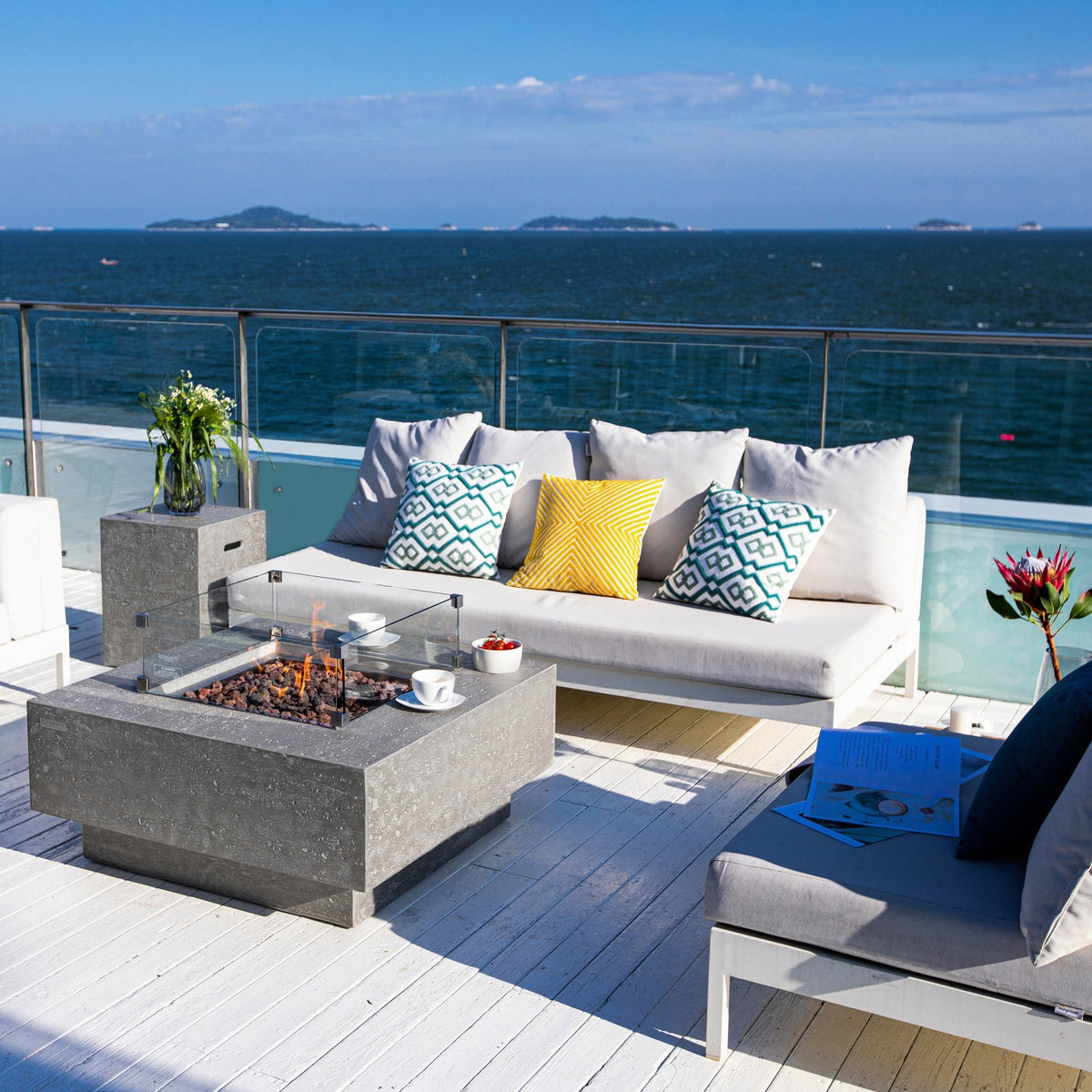 Manhattan fire table in a waterfront outdoor lounge; windscreen and decor sold separately